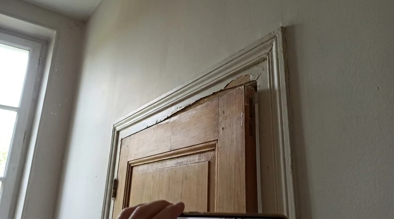 Haut d une porte qui coince contre un chambranle deforme et fendu